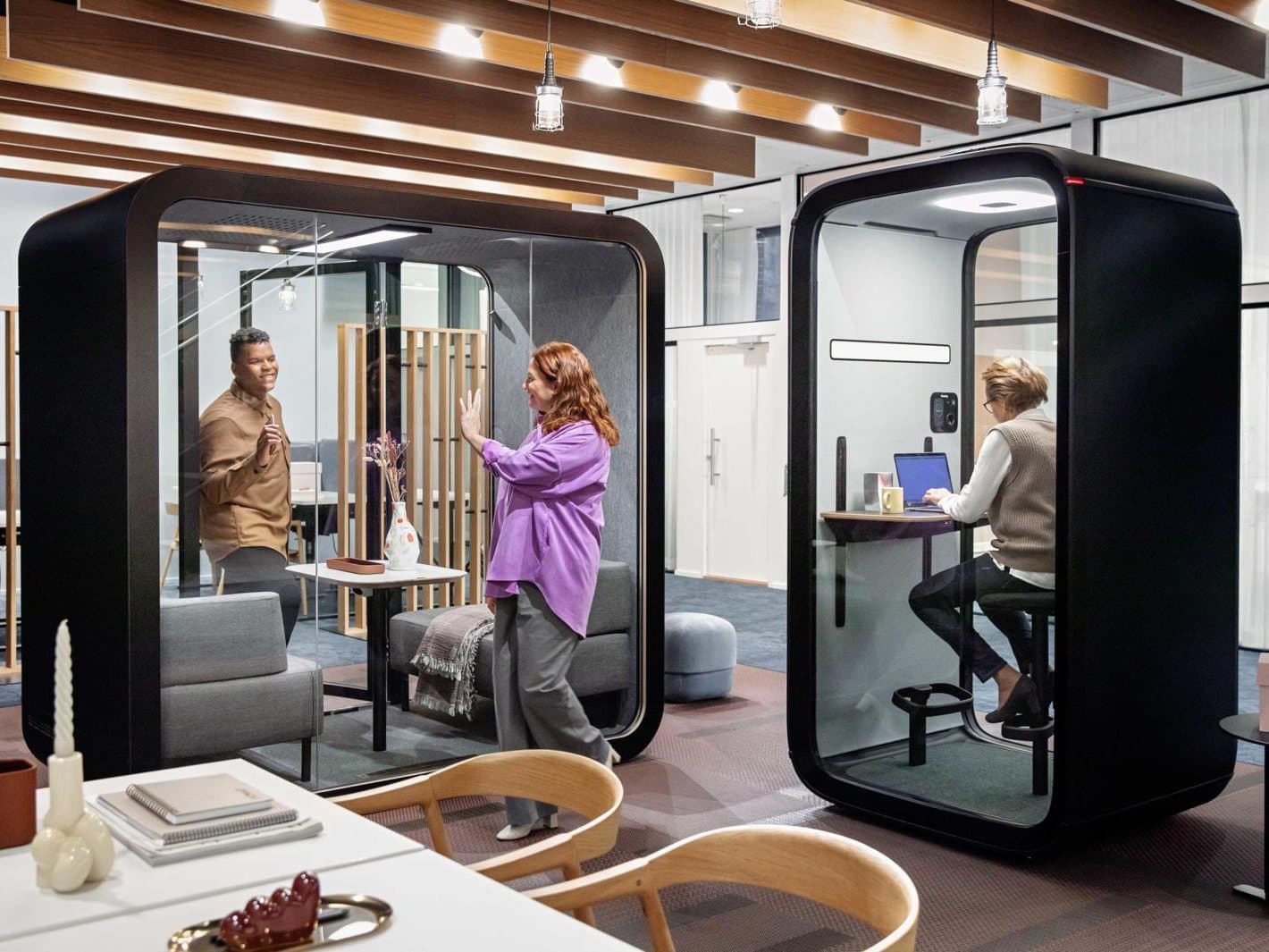 SiloPod acoustic office pods in an open-plan office — a meeting pod and a solo focus booth in use